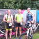 Celler Triathleten mit Fahrrädern vor dem Plakat des Hallig Dreeathlon 2025