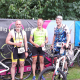 Celler Triathleten mit Fahrrädern vor dem Plakat des Hallig Dreeathlon 2025